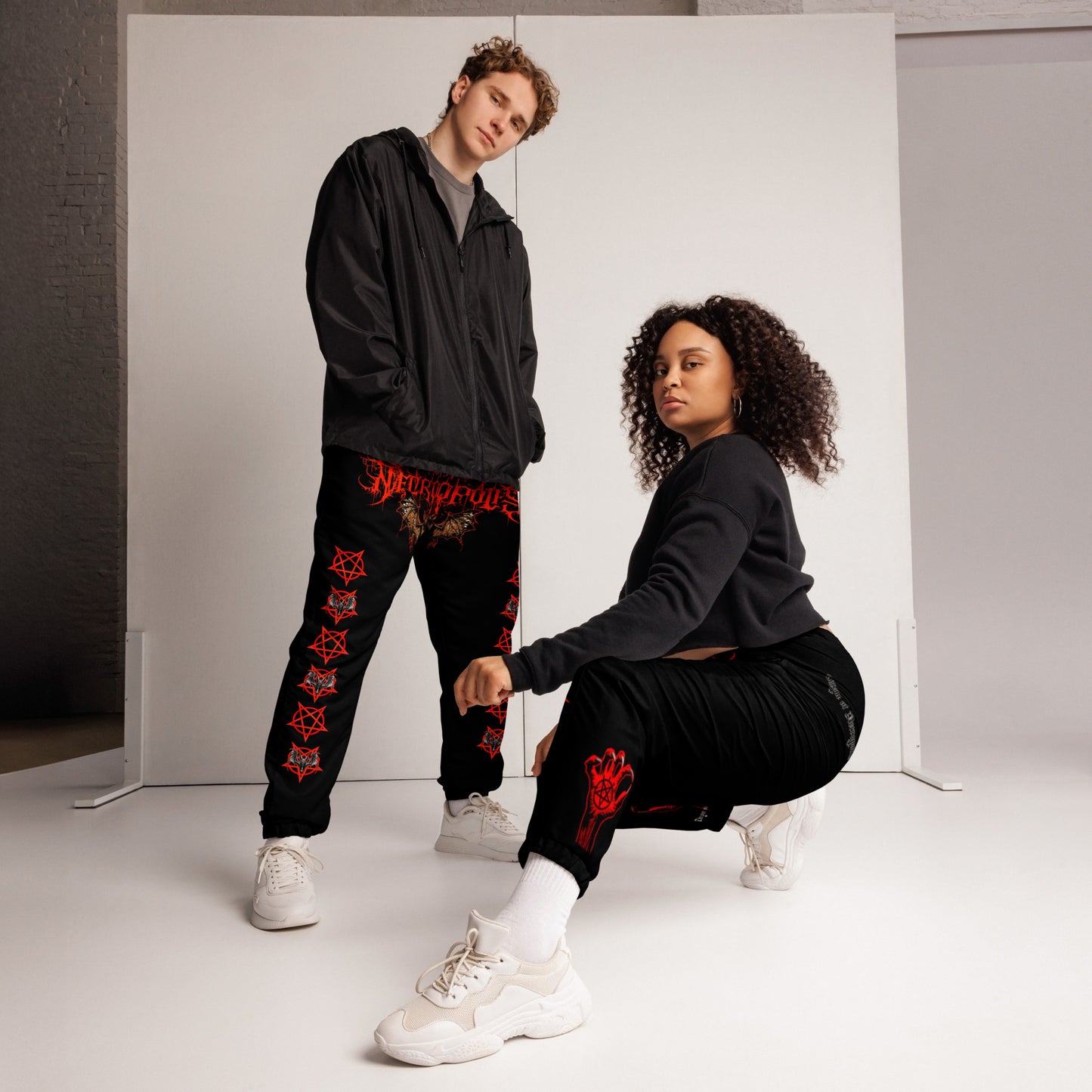 model wearing Unisex Black joggers pants sweats with red crotch print evil bat throne of necropolis red pentagram with bat both legs print demon satan evil red hands with black palm pentagram on back ankles blood wing angled front view