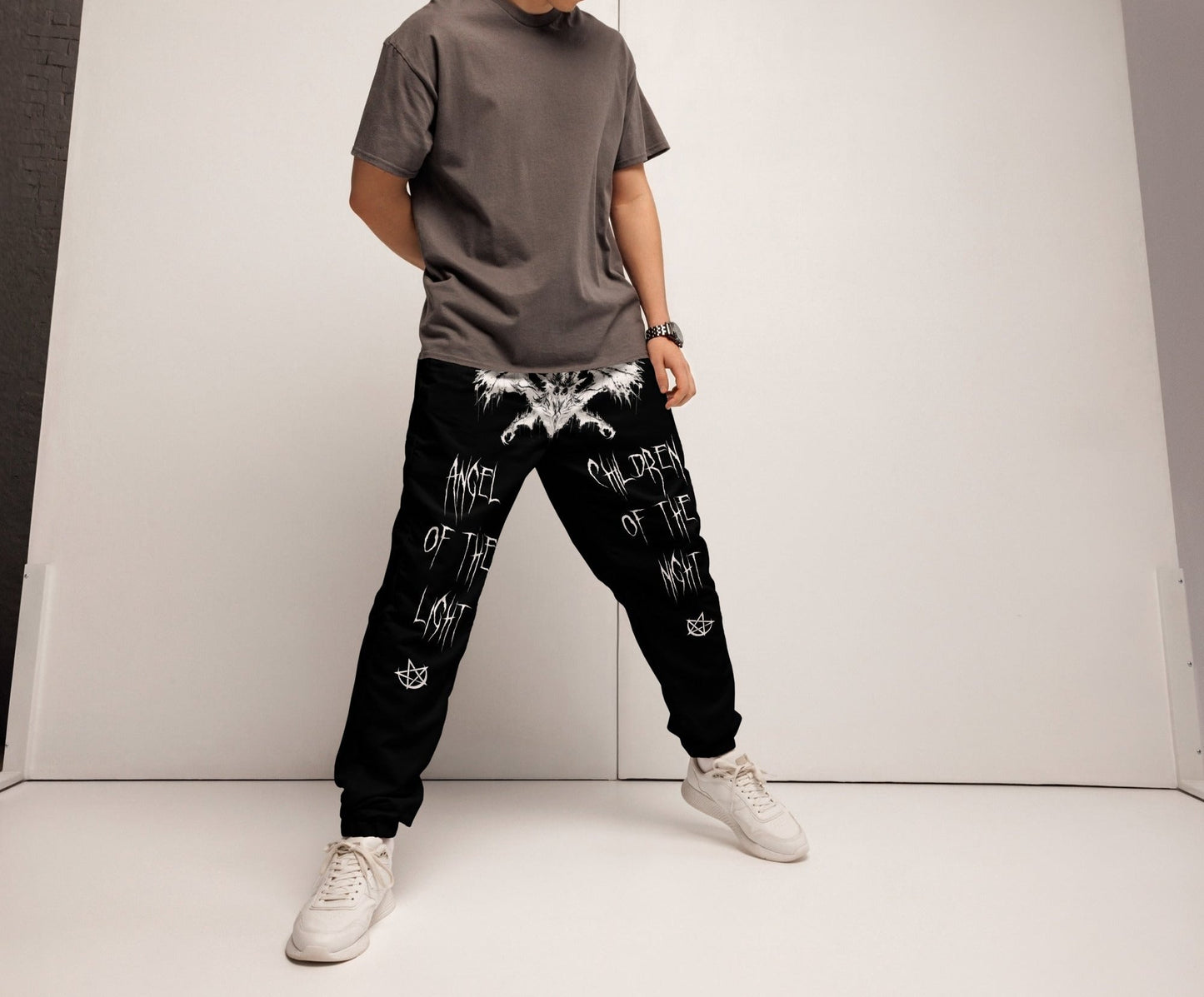 model wearing Black Joggers Pants Sweats Wing Demon Print in white on crotch Throne of Necropolis White Print on back Angel of the light leg Print and Children of the night Leg Print Alternative Streetwear Goth Witchcraft Occult Crescent Moon Pentagram angled view baphomet