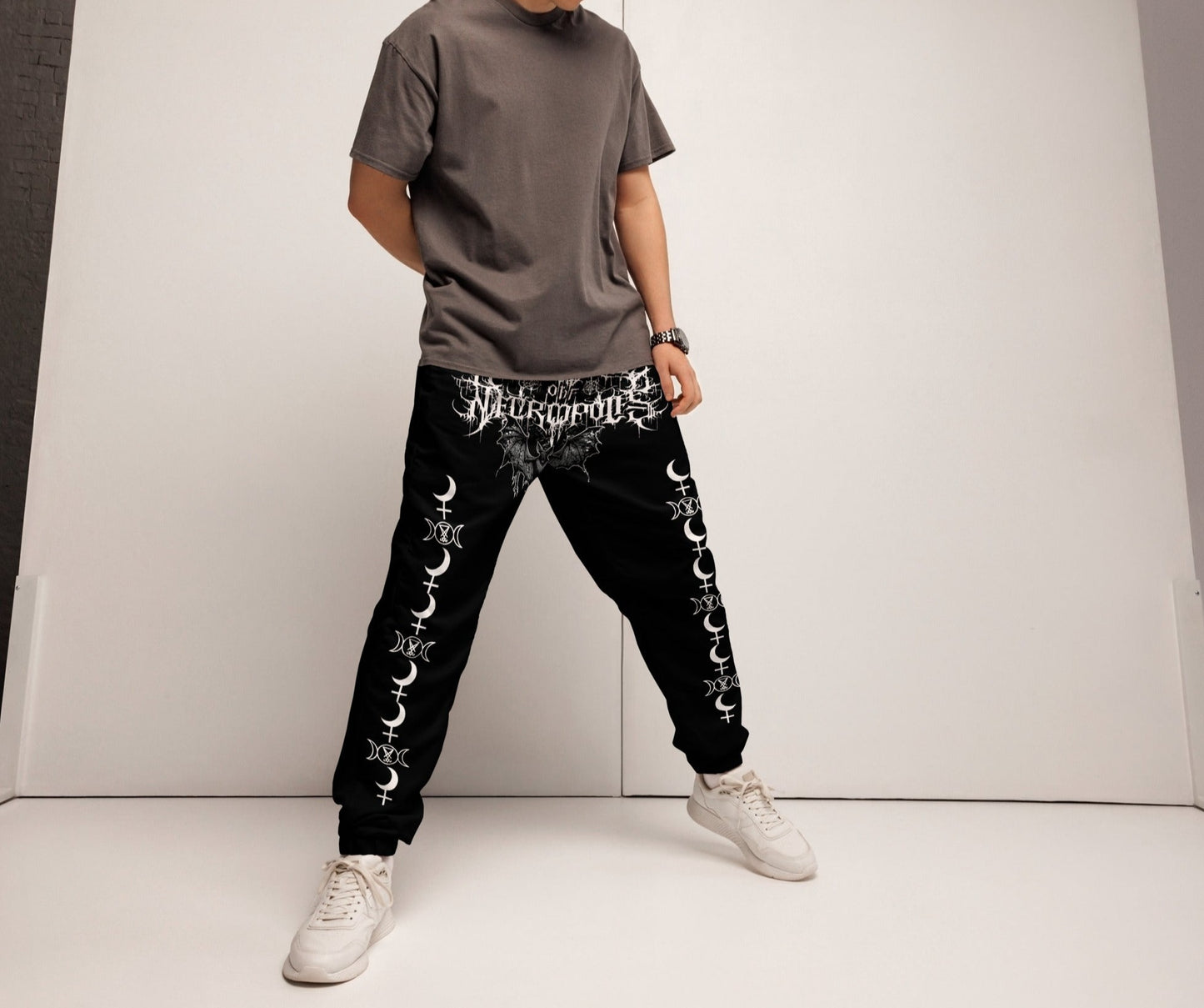 model wearing black joggers pants sweat with evil bat and throne of necropolis print on crotch with lilith seal moon and lucifer seal triple moon in white print angled view